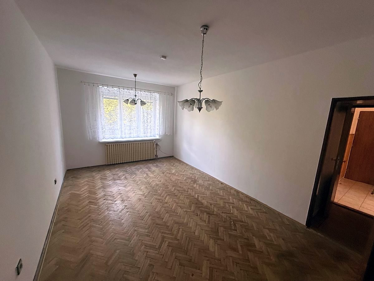 Prázdný obývací pokoj s parketami a dvěma okny